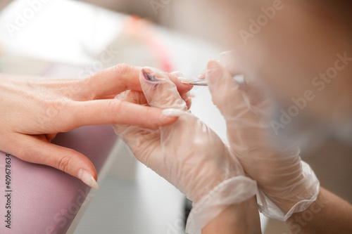 Professional manicure master is doing nails for happy client in beauty salon