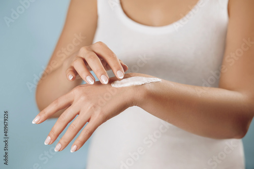 Closeup of female hands applying hand cream  lotion. Hand skin care. Beautiful woman hands with french manicure. Beauty and body careconcept