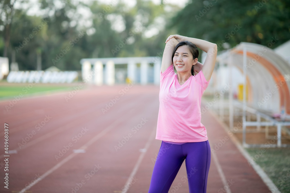 Asian girl is stretching her body warm muscles before going out for a run at the park Asian girl is stretching her body warm muscles before going out for a run at the park