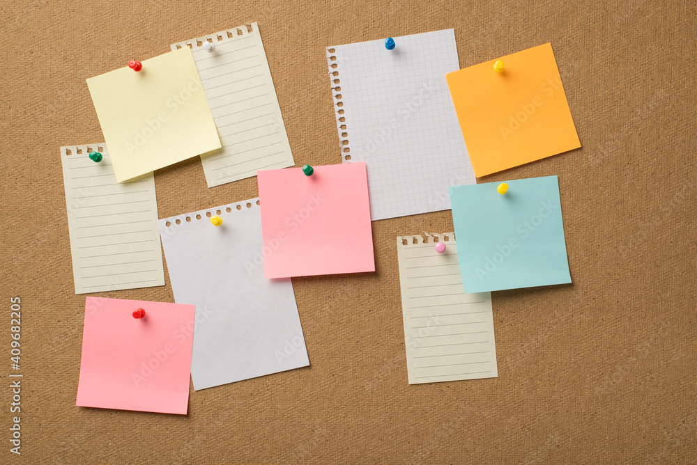 Photo of lot many colorful stickers and paper from copybooks attached to the wooden board with colorful pins Photo of lot many colorful stickers and paper from copybooks attached to the wooden board with colorful pins