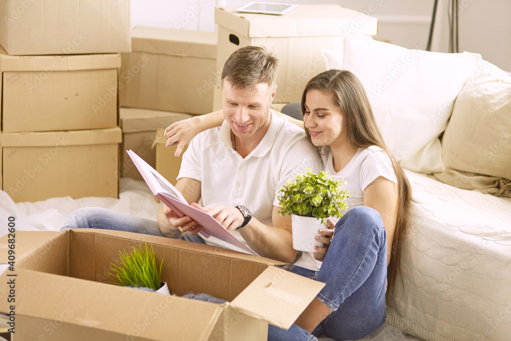Portrait of happy couple looking at laptop computer together sitting in new house, surrounded with boxes Portrait of happy couple looking at laptop computer together sitting in new house, surrounded with boxes