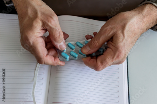 Close up of old man taking antibiotic and pills at home. Daily norm of vitamins, effective drugs, modern pharmacy for body and mental health concept. Mature man taking a pill while sitting on the bed.