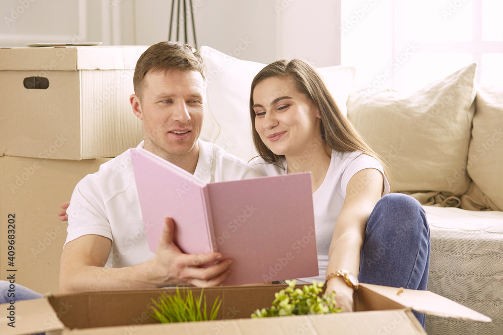 Portrait of happy couple looking at laptop computer together sitting in new house, surrounded with boxes Portrait of happy couple looking at laptop computer together sitting in new house, surrounded with boxes