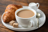 Coffee with milk and french croissant on a plate. Breakfast in cafe on a wooden table background