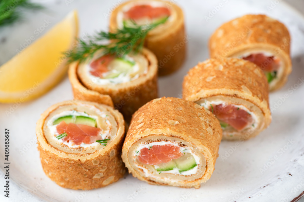 Salmon and cream cheese crepe rolls. Appetizer rolls with smoked salmon, cucumber and cream cheese with dill