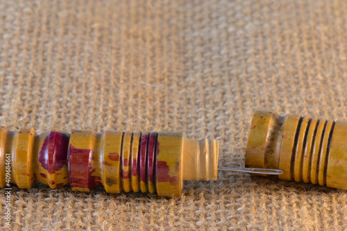 Estuche de madera en forma de tubo para guardar agujas de coser y enroscar hilo en sus ranuras externas. photo