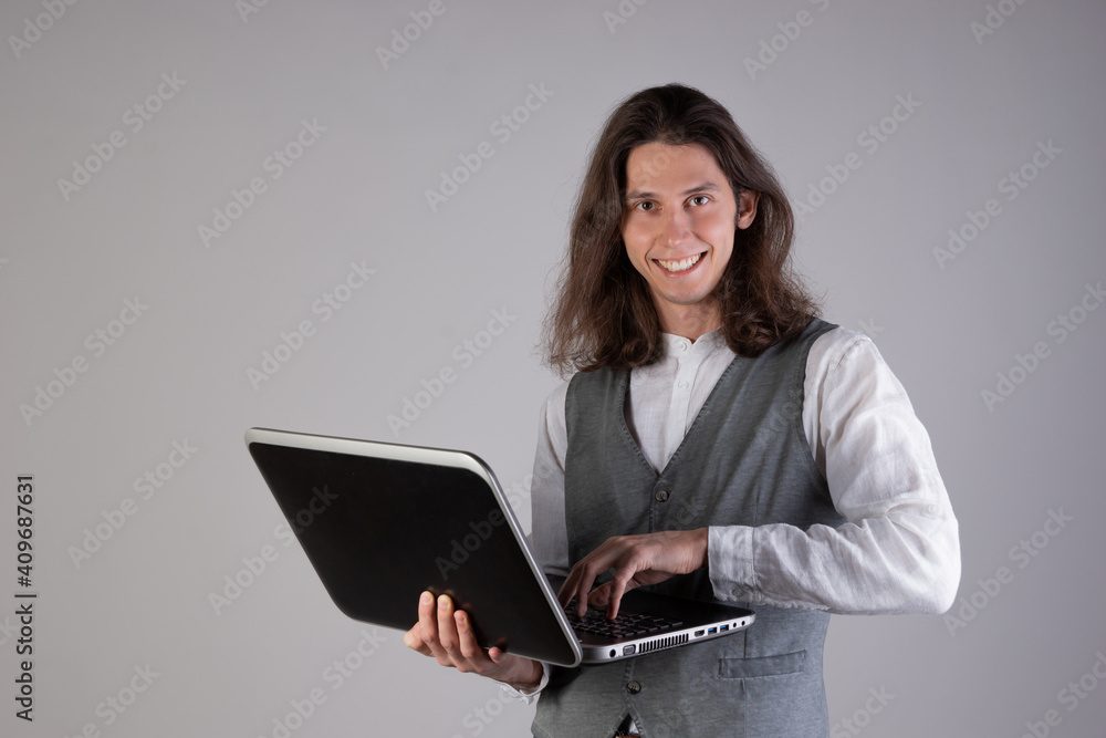 Training and new technologies, online courses, e-learning. A young man with long hair. A student is holding a laptop Training and new technologies, online courses, e-learning. A young man with long hair. A student is holding a laptop