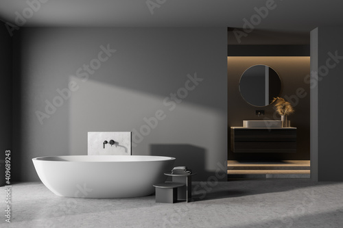 Modern bathroom interior with dark concrete walls, gray floor, white bathtub and sink. 3d rendering