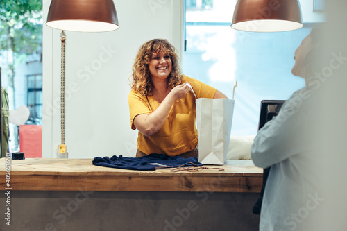 Tableau sur toile Store owner packing customer purchases in paper bag