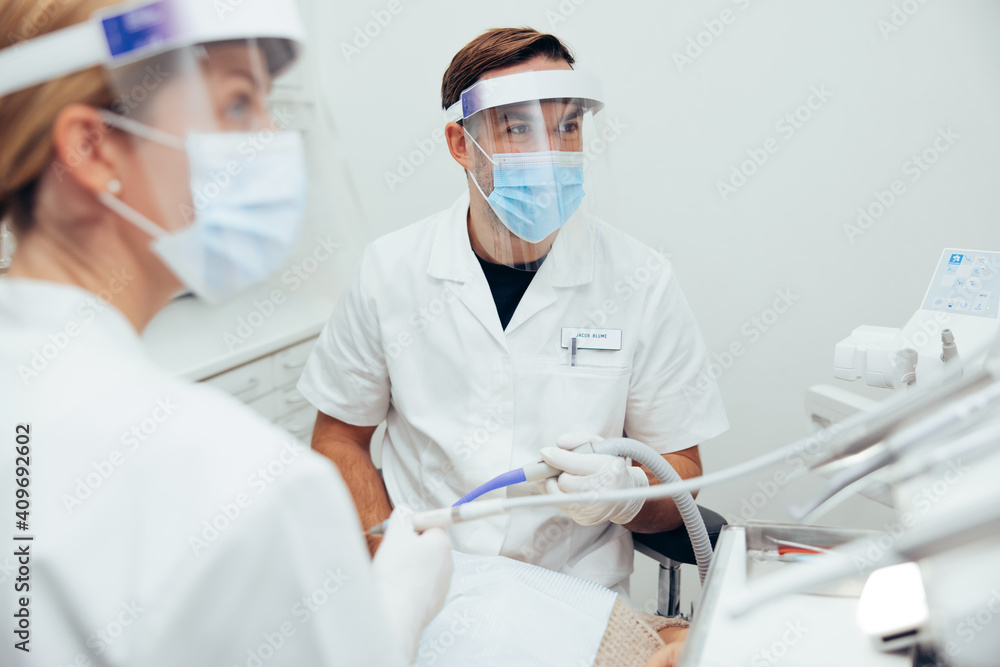 Dentists treating a patient with face shields Dentists treating a patient with face shields