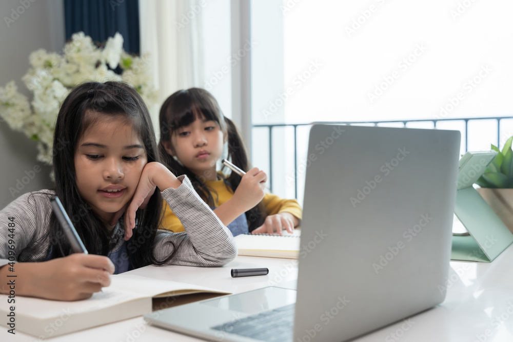 Little Asian girl studying online lesson at home with sister. Homeschooling during quarantine online education concept. Little Asian girl studying online lesson at home with sister. Homeschooling during quarantine online education concept.