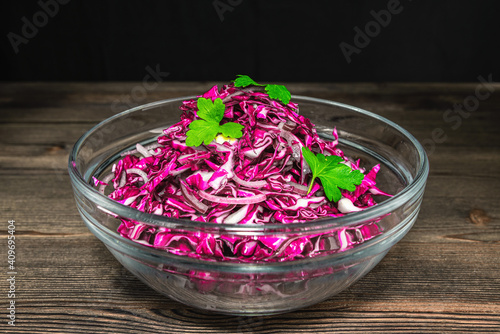 Chopped red cabbage in a glass dish on a wooden table background