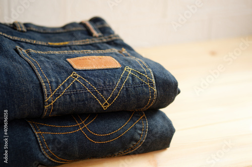 Jeans trousers stacked on wooden background with copy space for text design