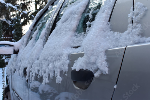 Zaśnieżony i oblodzony samochód w czasie zimy.