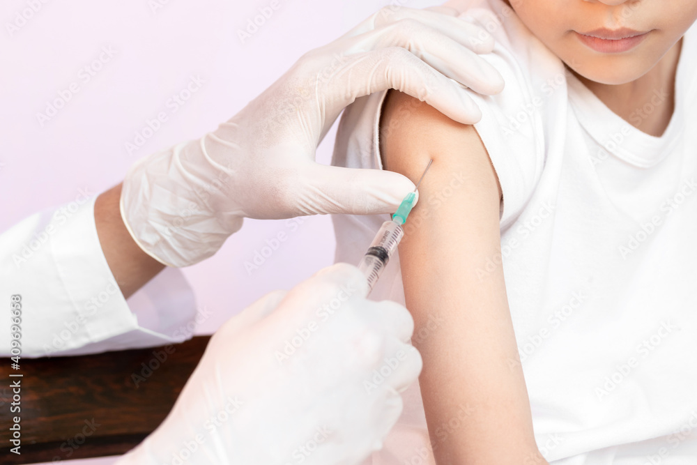 A happy kid is being vaccinated. doctor vaccinating little boy. Doctor examining a child in a hospital. A happy kid is being vaccinated. doctor vaccinating little boy. Doctor examining a child in a hospital.