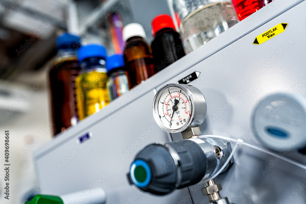 Closeup of pressure manometer measuring gas pressure, industry background, selective focus, pipes and valves in the chemistry laboratory Closeup of pressure manometer measuring gas pressure, industry background, selective focus, pipes and valves in the chemistry laboratory