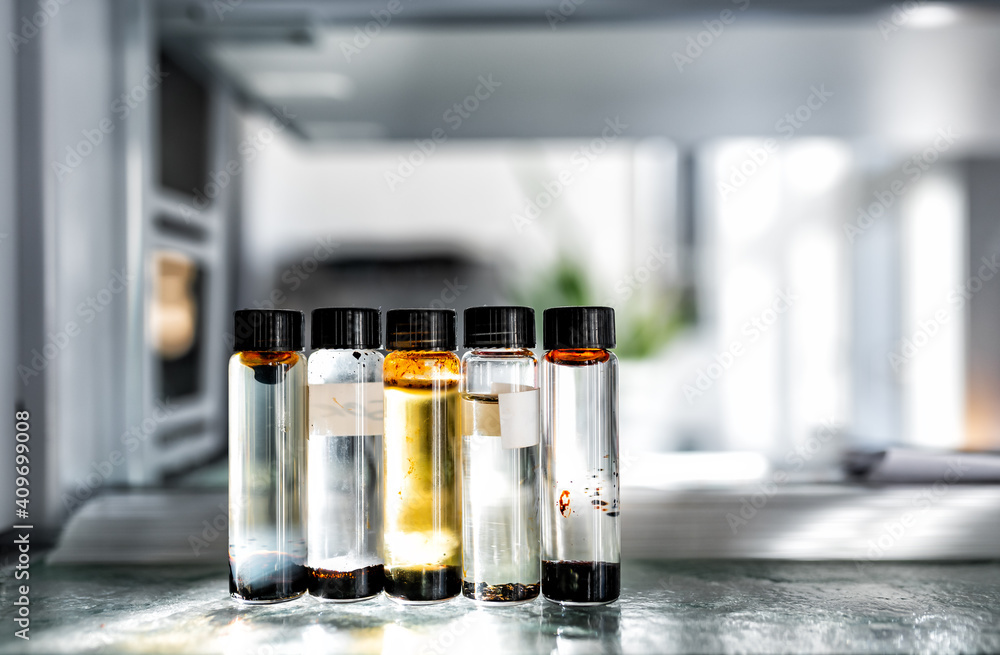 Closeup of laboratory glassware filled with orange and brown oily liquids, science and research background, selective focus Closeup of laboratory glassware filled with orange and brown oily liquids, science and research background, selective focus