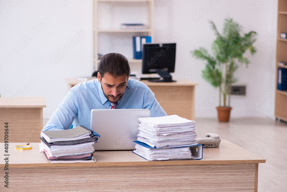 Young male employee unhappy with excessive work in the office Young male employee unhappy with excessive work in the office