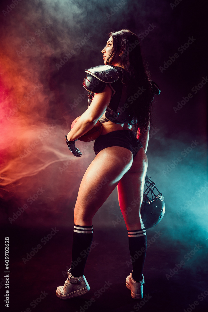 Young brunette wearing sexy uniform of rugby football player posing with ball.
