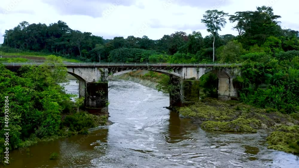 Old bridge over a stormy river in the rainforest. River in the jungle of Africa Old bridge over a stormy river in the rainforest. River in the jungle of Africa
