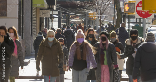 Crowd of people walking street wearing masks