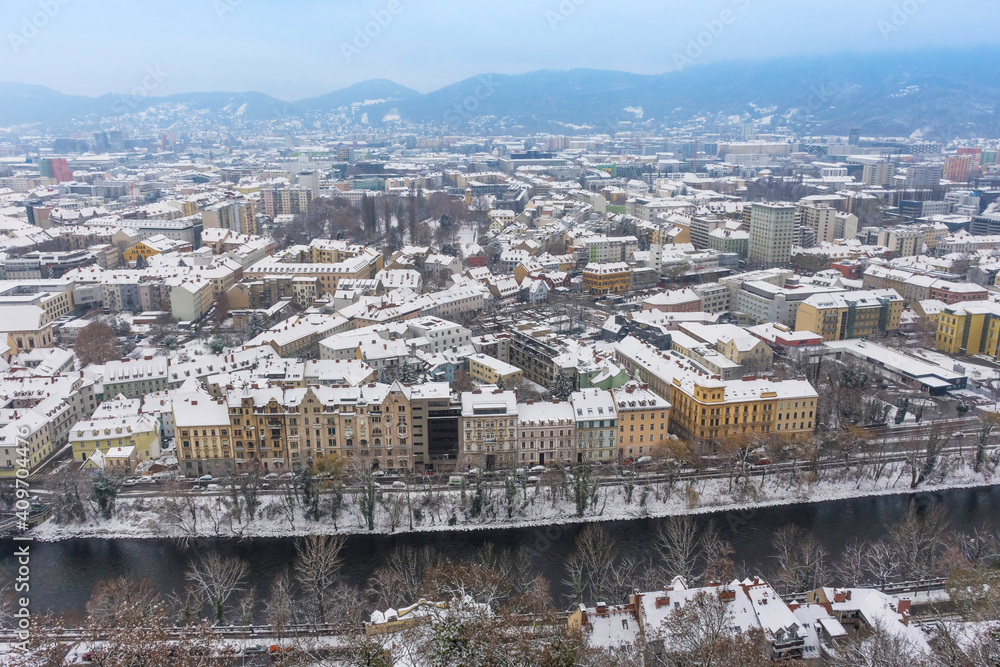 Obraz premium Cityscape of Graz with Mur river and historic buildings rooftops in winter with snow, in Graz, Styria region, Austria