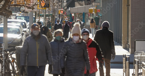 Crowd of people walking street wearing masks