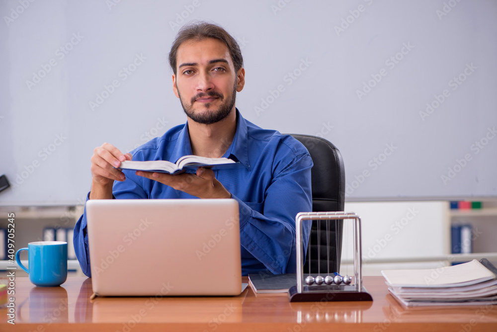 Young male teacher physicist sitting in the classroom Young male teacher physicist sitting in the classroom