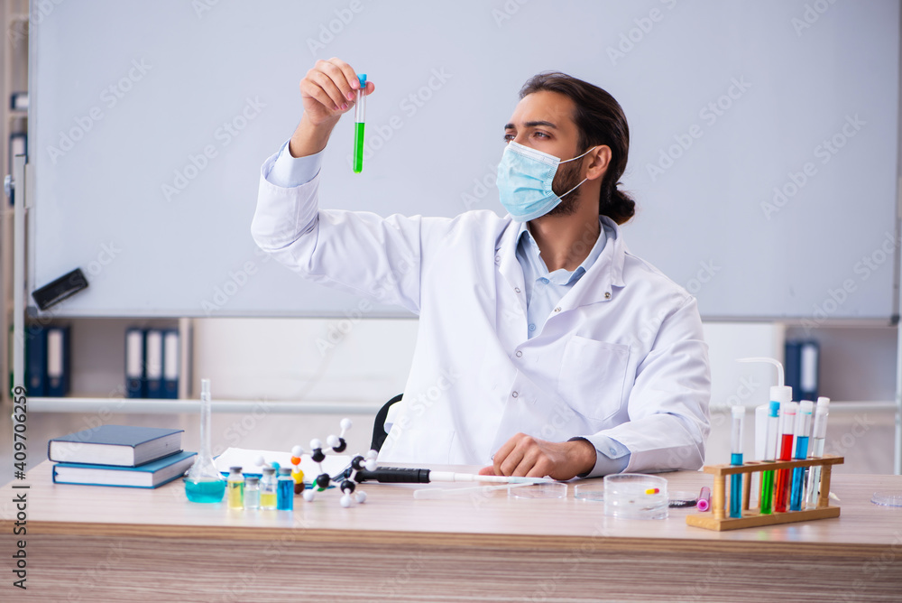 Young male chemist teacher sitting in the classroom Young male chemist teacher sitting in the classroom