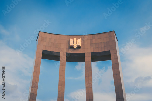 Arch with the emblem of Ukraine on a clear blue sky.