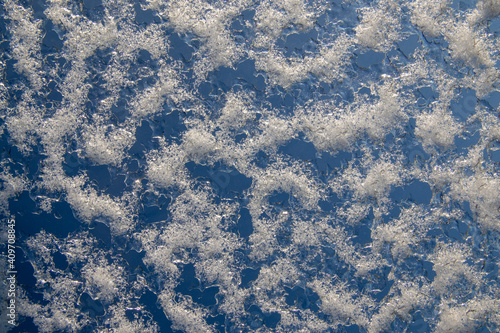 Texture of frozen glass, wet cold glass on blue background, frozen patterns on the window