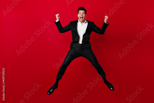 Excited european man jumping in valentine's day. Studio shot of male model in suit dancing and smiling.