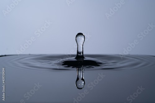 High resolution macro photograph of a colorful water drop splashing into water