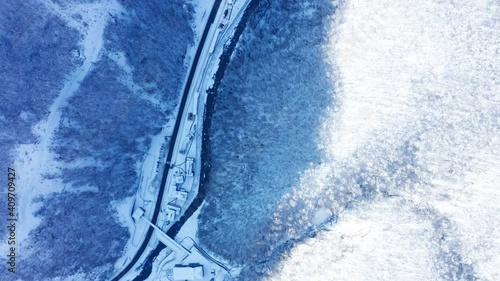 Drone flies over trees with snow  in the forest and river  in winter