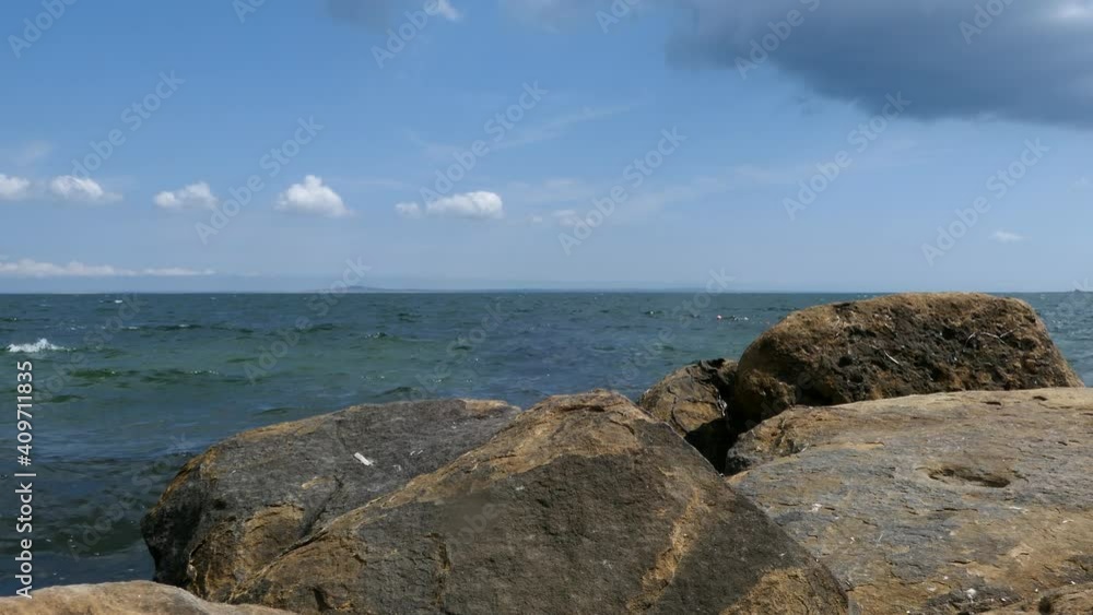Coastline With Rocks On In Front Of Wide View Of Sea In Sunny Summer Day. Coastline With Rocks On In Front Of Wide View Of Sea In Sunny Summer Day.