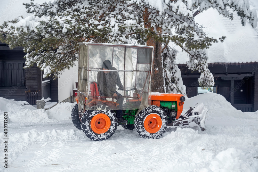 Orange mini tractor clears snow Orange mini tractor clears snow
