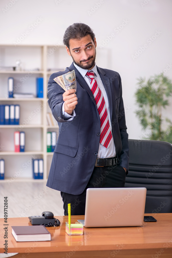 Fototapeta premium Young male employee holding banknotes in the office