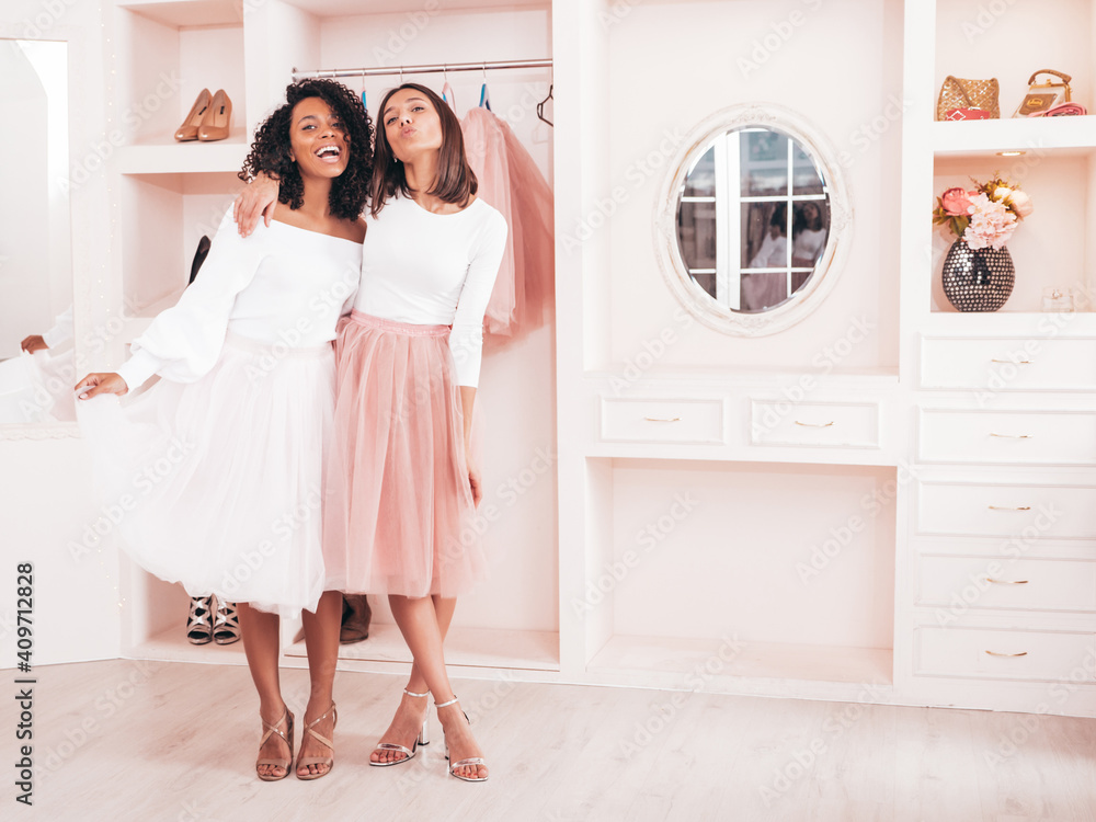 Two young beautiful smiling international hipster female in trendy summer dresses. Sexy carefree women posing in pink wardrobe. Positive models having fun. Concept of friendship Two young beautiful smiling international hipster female in trendy summer dresses. Sexy carefree women posing in pink wardrobe. Positive models having fun. Concept of friendship