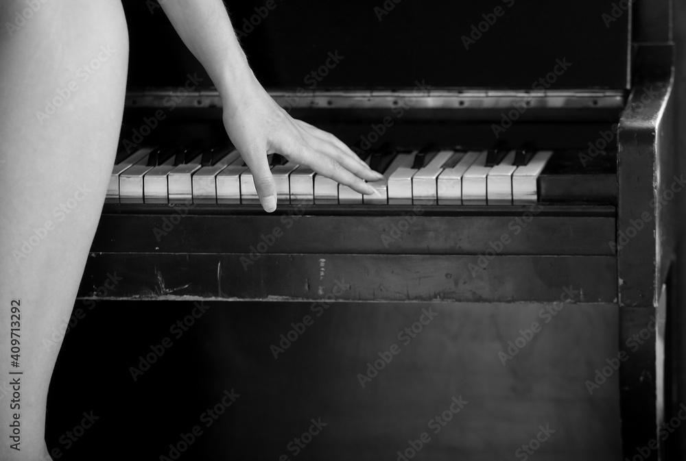 A young attractive girl plays the piano, a naked figure Photos | Adobe Stock