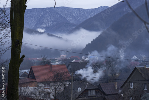 Mountain village in the fog. Smoke coming out of the pipes of the stove heating