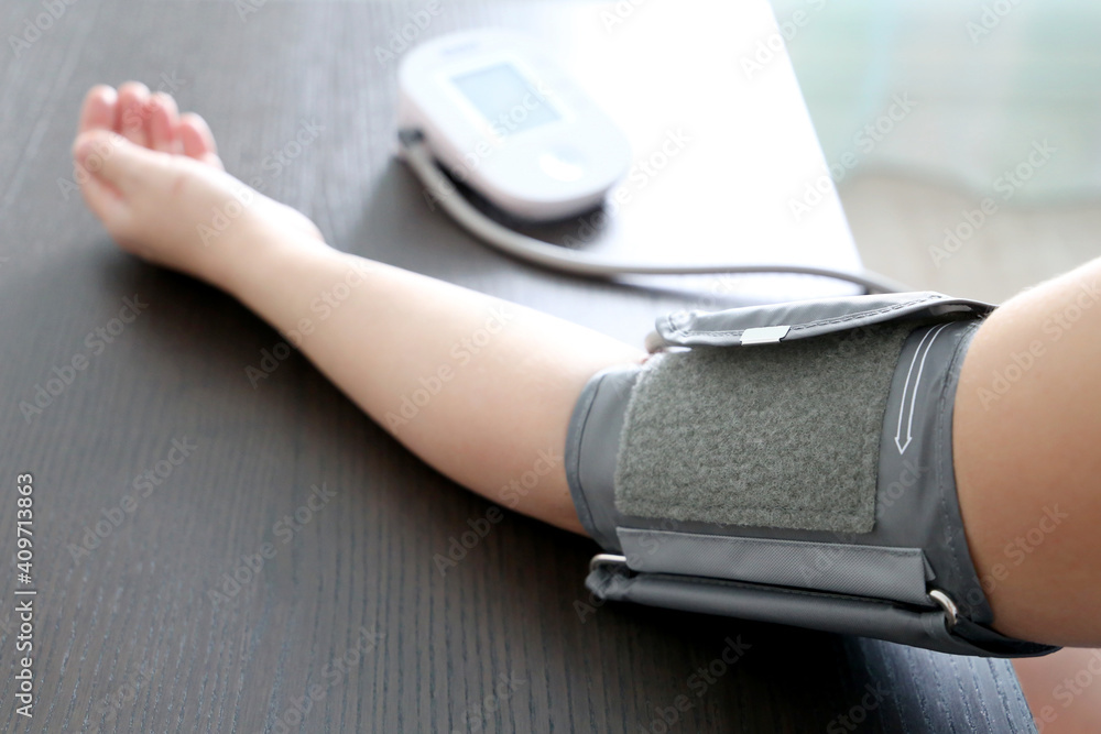 Fototapeta premium Woman measuring blood pressure with electronic digital tonometer, female hand close up. Health care, hypertension and cardiology concept
