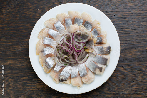 pieces of salted fish with pickled onions. Scandinavian herring appetizer on a white plate. view from above