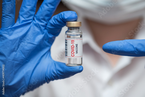 Vaccine in ampoule. From the coronavirus. The doctor keeps in blue gloves.