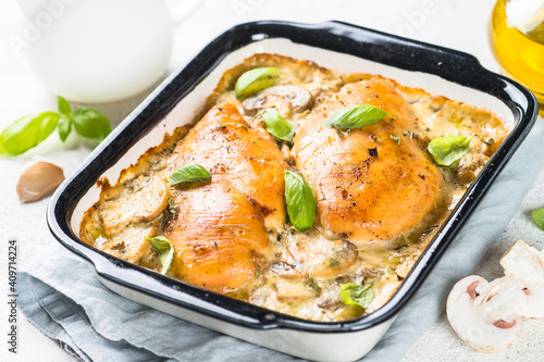 Baked chicken breast with mushrooms in cream sauce on white kitchen table.