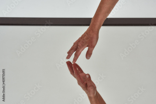 Close up shot of female hand touching reflective surface of mirror on the floor isolated over light background photo