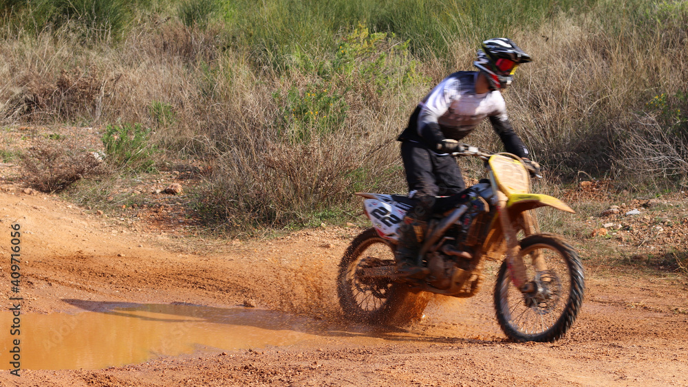 Obraz premium Professional dirt bike motocross rider performing stunts in extreme mud terrain track