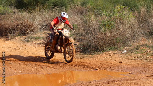 Professional dirt bike motocross rider performing stunts in extreme terrain track