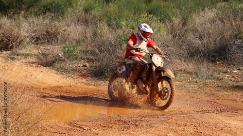 Professional dirt bike motocross rider performing stunts in extreme mud terrain track