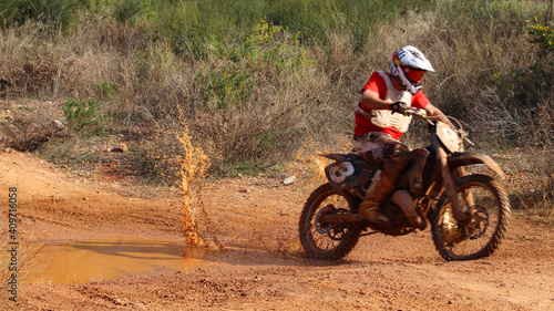 Close-up of motocross wheel passing over mud and dirt water pond freezing motion
