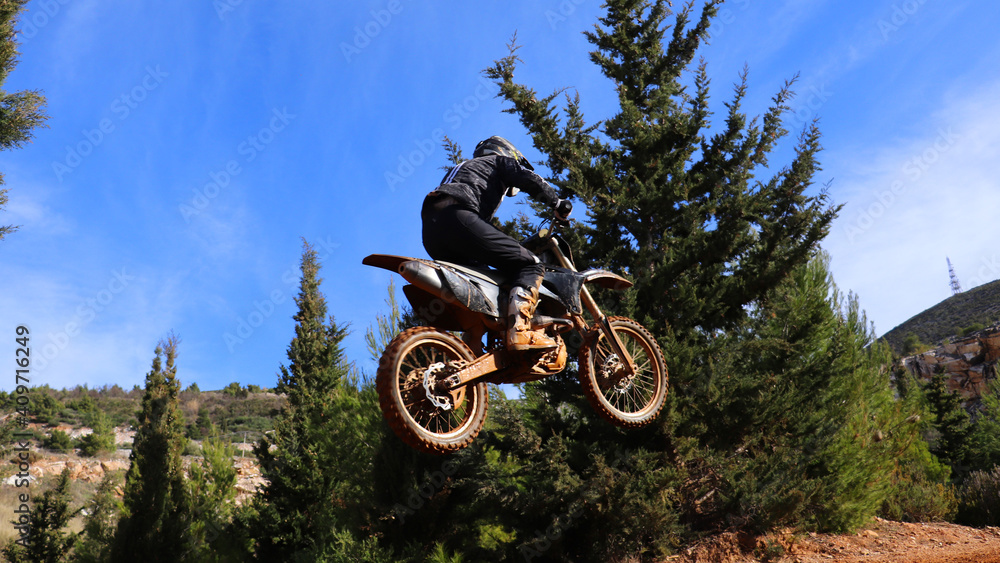 Professional dirt bike motocross rider performing stunts and flying from jump in extreme terrain track Professional dirt bike motocross rider performing stunts and flying from jump in extreme terrain track